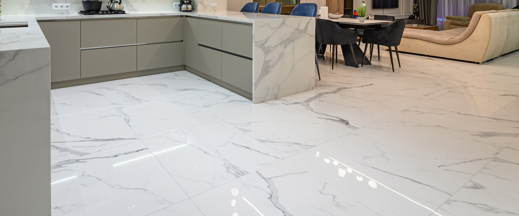 A modern kitchen with sleek cabinetry, marble countertops, and flooring, showcasing a clean and spacious design.