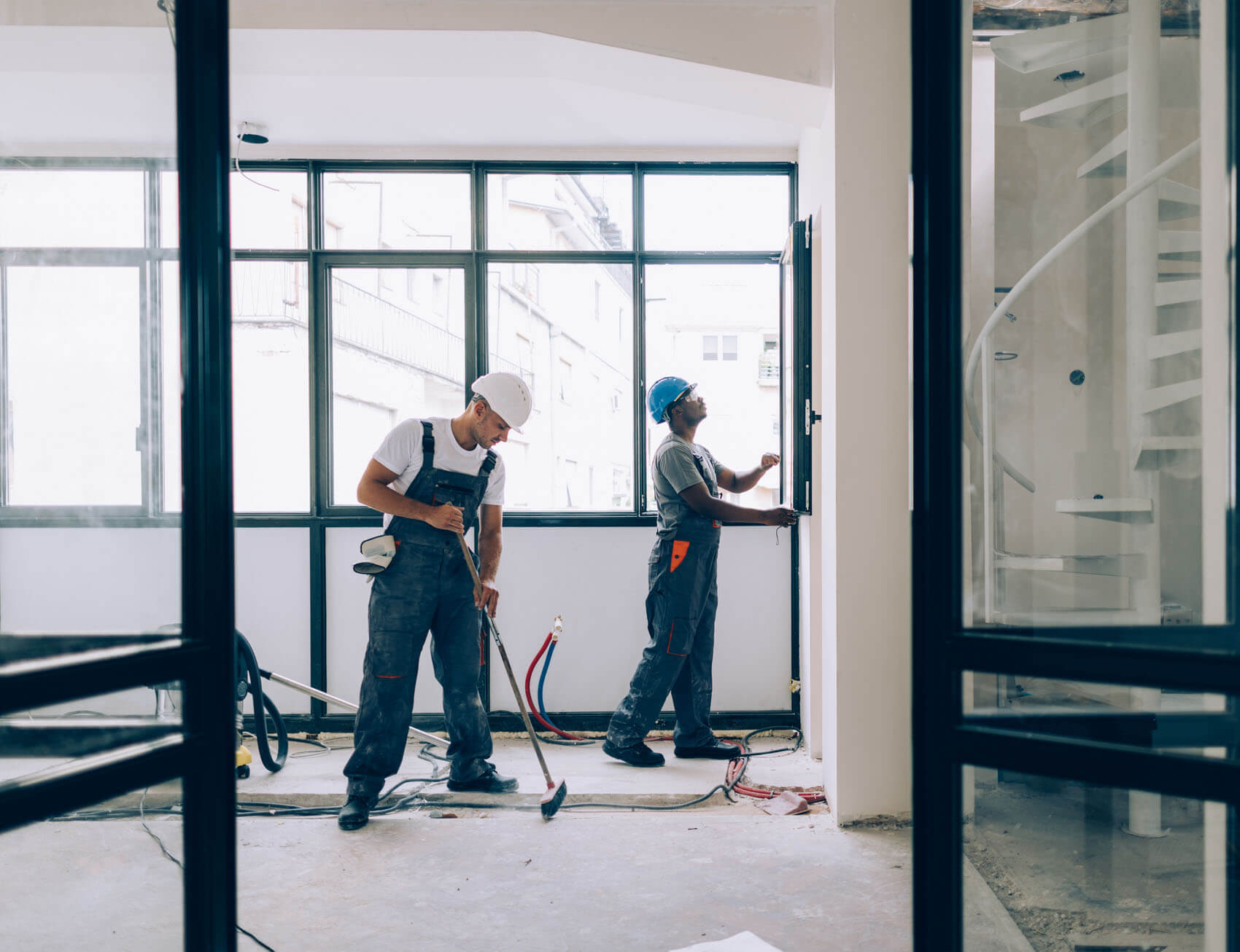 Two men doing renovation work together in an unfinished commercial building.